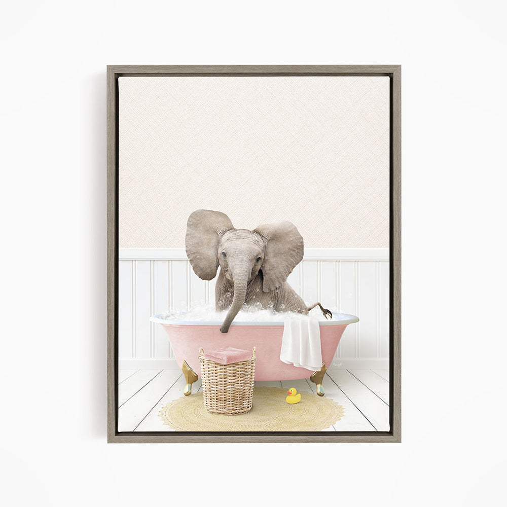 A gray elephant is sitting in a pink bathtub filled with water, surrounded by a yellow rubber duck and a basket of bath toys.