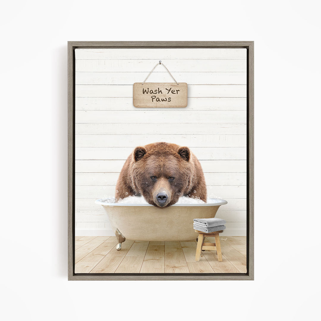 A brown bear is sitting in a bathtub, with a sign above it that says "Wash Your Paws".