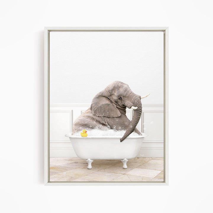 A gray elephant is sitting in a white bathtub filled with water, with a yellow rubber duck floating nearby.