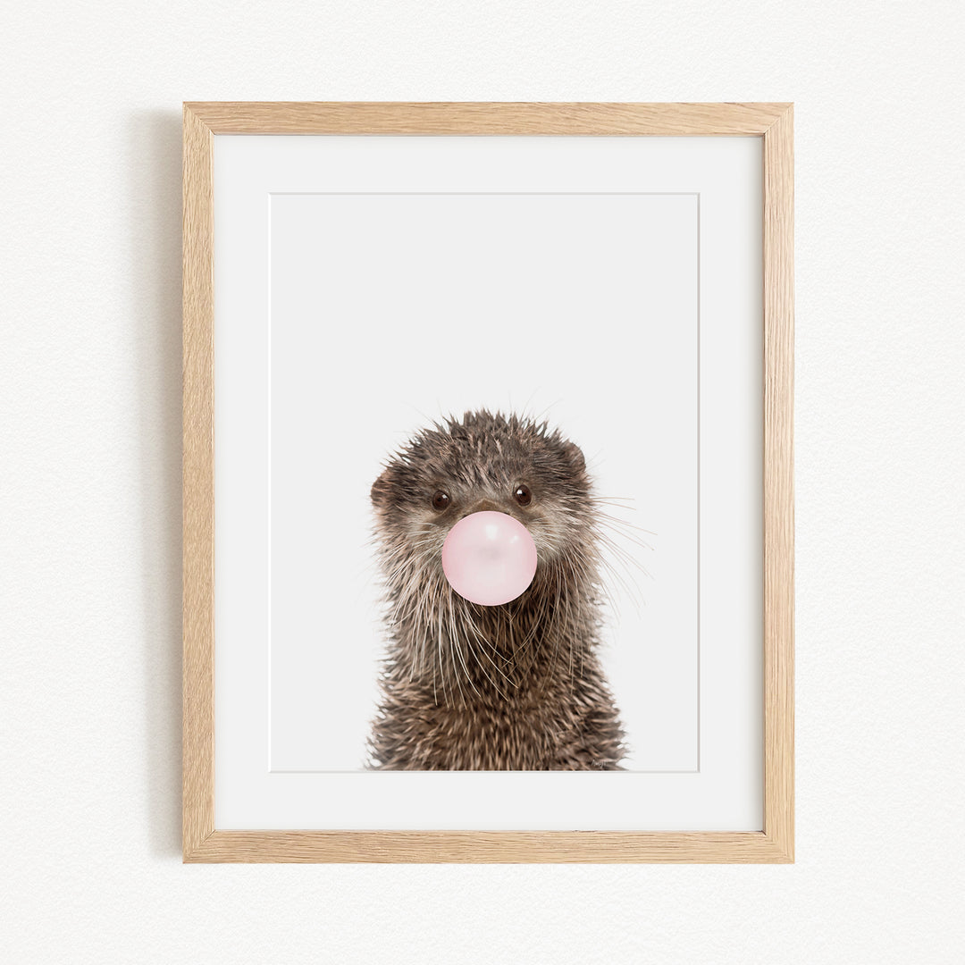 A picture of an otter blowing a bubble with a pink bubble gum bubble.