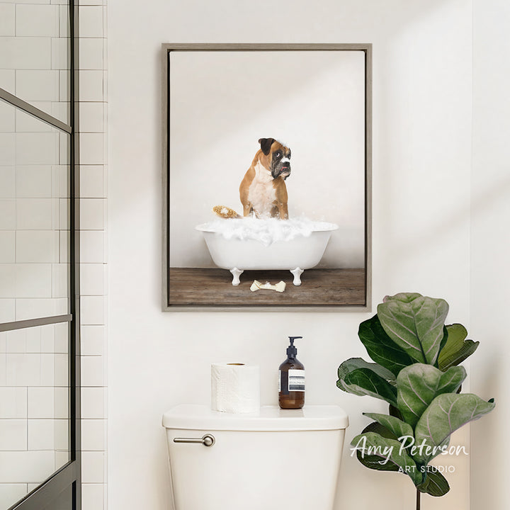 A framed image of a dog sitting in a bathtub, surrounded by bubbles, is displayed on the wall above a white toilet in a bathroom.