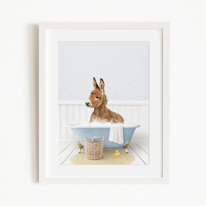 A donkey is sitting in a blue bathtub filled with water, surrounded by rubber ducks.