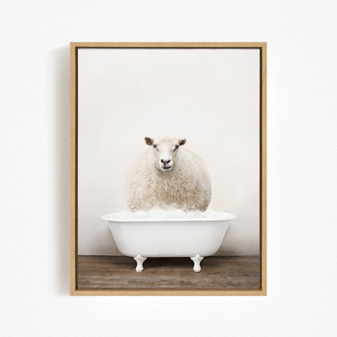 A fluffy white sheep sits in a white bathtub filled with bubbles, looking directly at the camera.