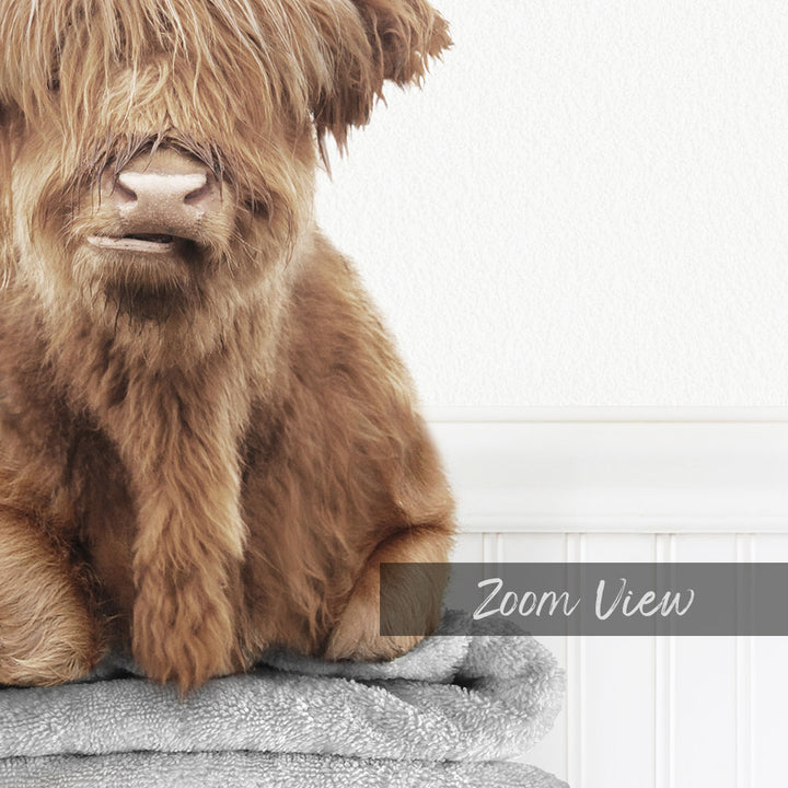 A close-up of a shaggy, brown animal with a textured coat, sitting on a gray towel.