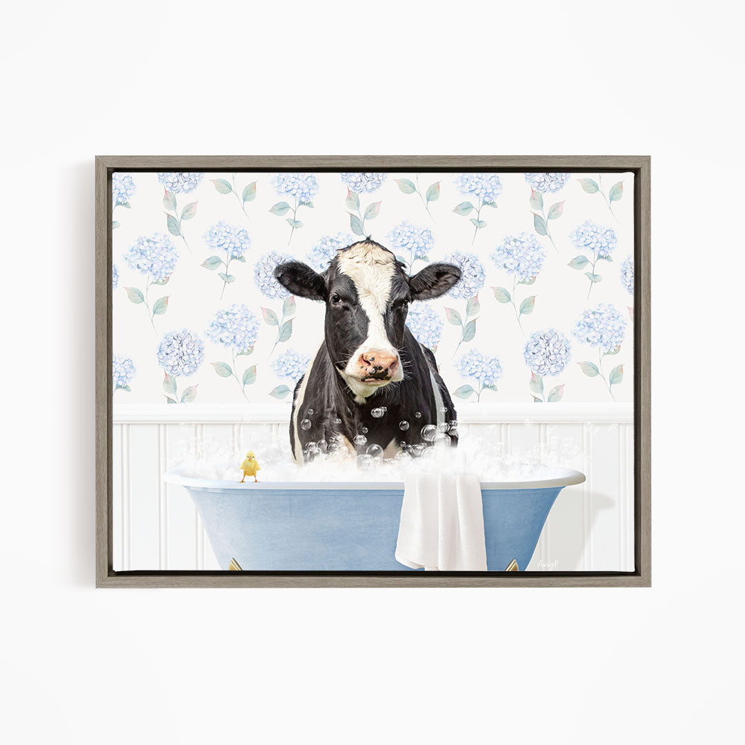 A black and white cow is sitting in a blue bathtub filled with bubbles, with a yellow bird perched on the edge of the tub.