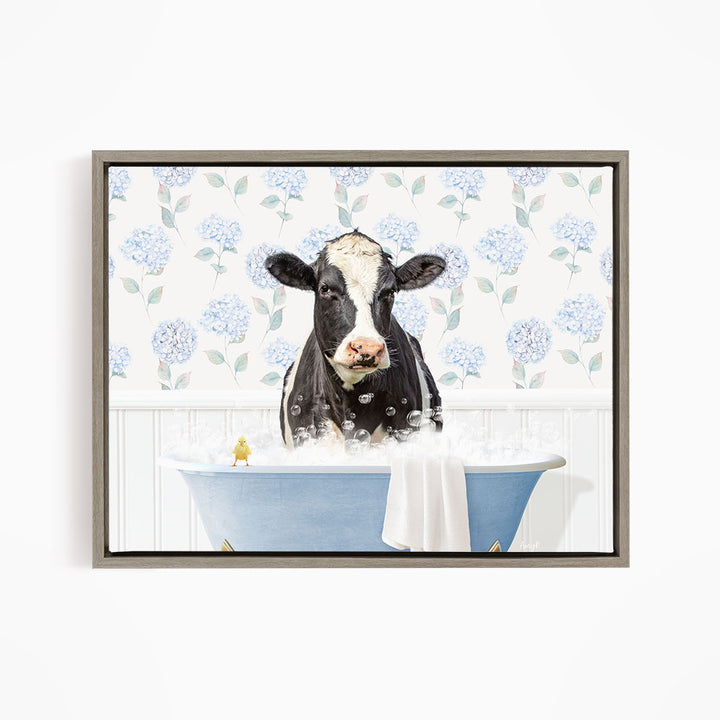 A black and white cow is sitting in a blue bathtub filled with bubbles, with a yellow bird perched on the edge of the tub.