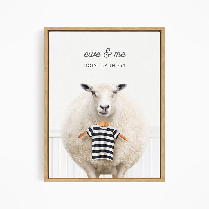 A framed image depicting a sheep standing in front of a white wall, with a striped shirt hanging from its neck.