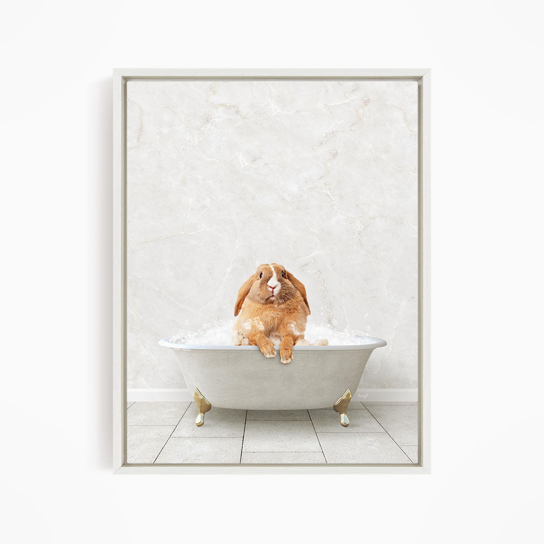 A brown rabbit sitting in a white bathtub filled with bubbles, looking up at the camera.