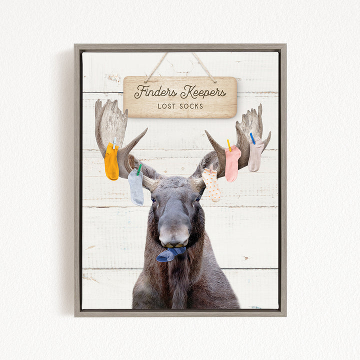 A framed image of a moose with a sign that says "Finders Keepers Lost Socks" hanging above it.