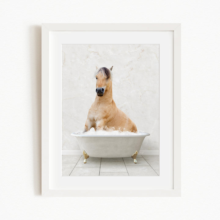 A light brown horse is sitting in a white bathtub filled with bubbles, creating a whimsical and playful scene.