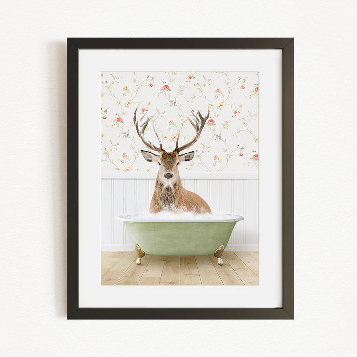 A deer with antlers is sitting in a green bathtub, surrounded by a floral wallpaper.