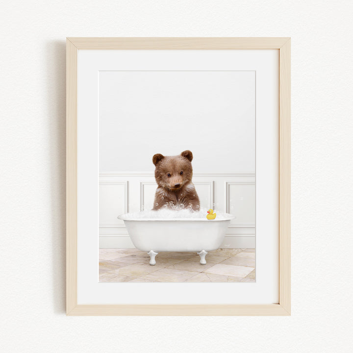 A brown bear sitting in a white bathtub filled with water, with a yellow rubber duck floating in the water.