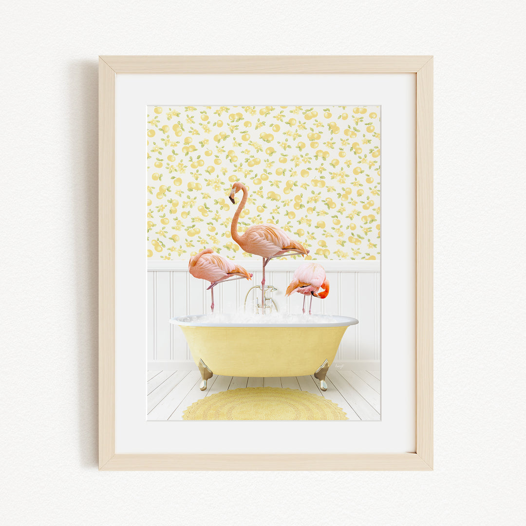 A framed image depicting three pink flamingos standing in a yellow bathtub, with a yellow floral wallpaper in the background.