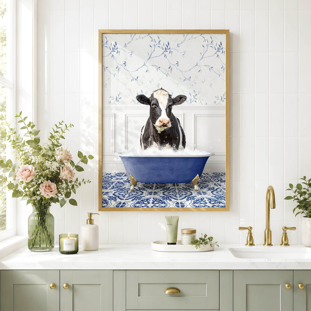 a framed picture of a cow sitting in a blue bathtub, surrounded by flowers and a white and blue floral pattern on the wall.