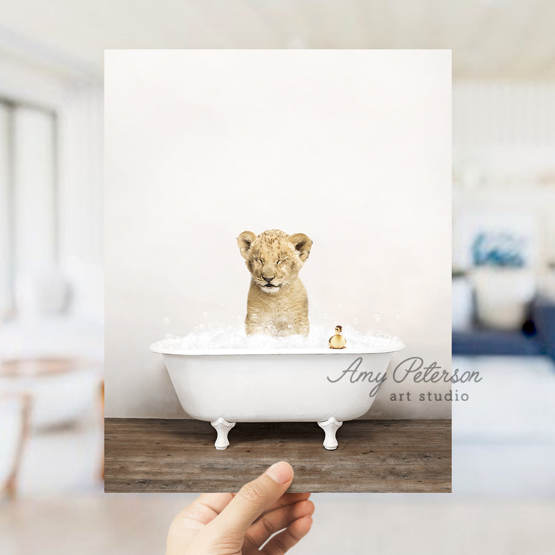 a hand holding up a photo of a lion cub in a bathtub