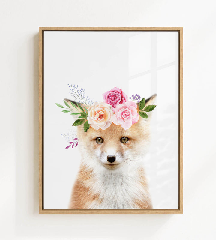 A framed print of a fox wearing a floral crown of pink and white roses and greenery.