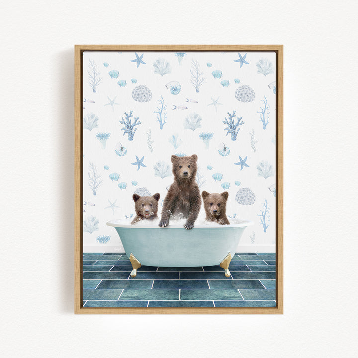 A framed print depicting three bears sitting in a bathtub, with a blue and white floral pattern on the wall behind them.