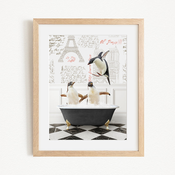A framed image depicting three penguins sitting in a bathtub, with one penguin jumping out of the tub.