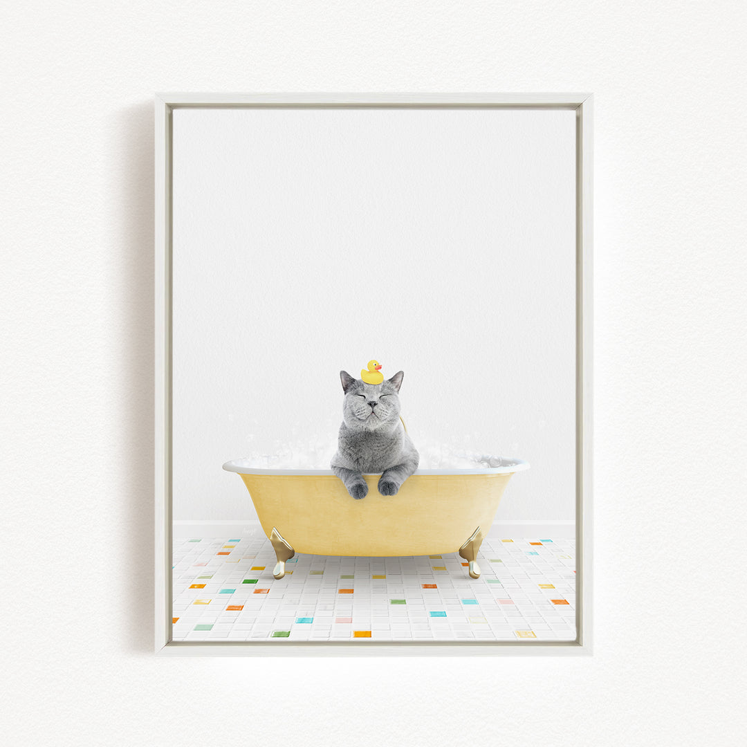A gray cat sitting in a yellow bathtub filled with bubbles, wearing a yellow hat.