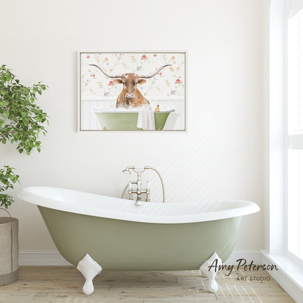 a green clawfoot bathtub with a framed picture of a bull with horns hanging above it on a white wall.