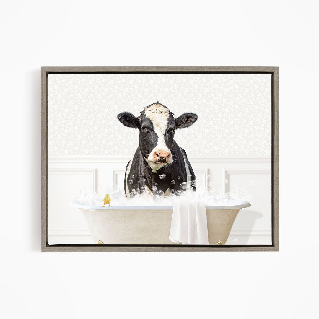 A black and white cow is sitting in a bathtub filled with bubbles, with a small yellow bird perched on the edge of the tub.
