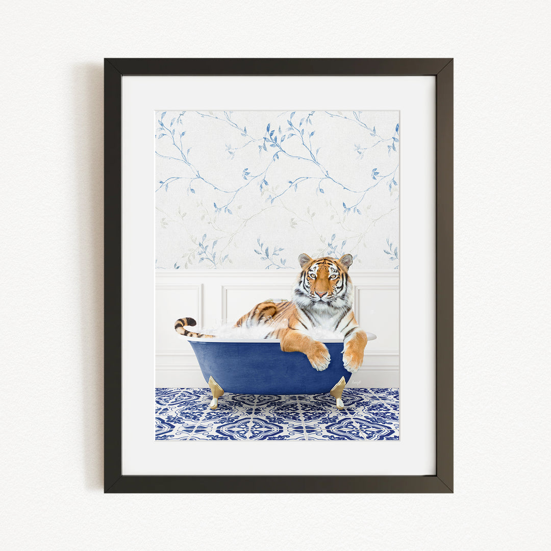 A tiger is sitting in a blue bathtub, surrounded by a patterned tile floor and a white wall with blue floral wallpaper.