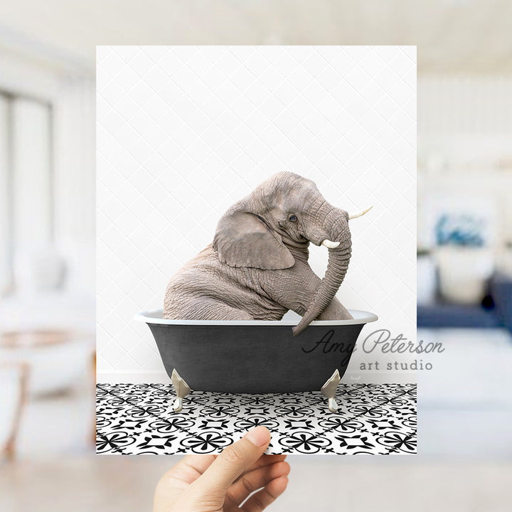 a person holding up a picture of an elephant in a bathtub