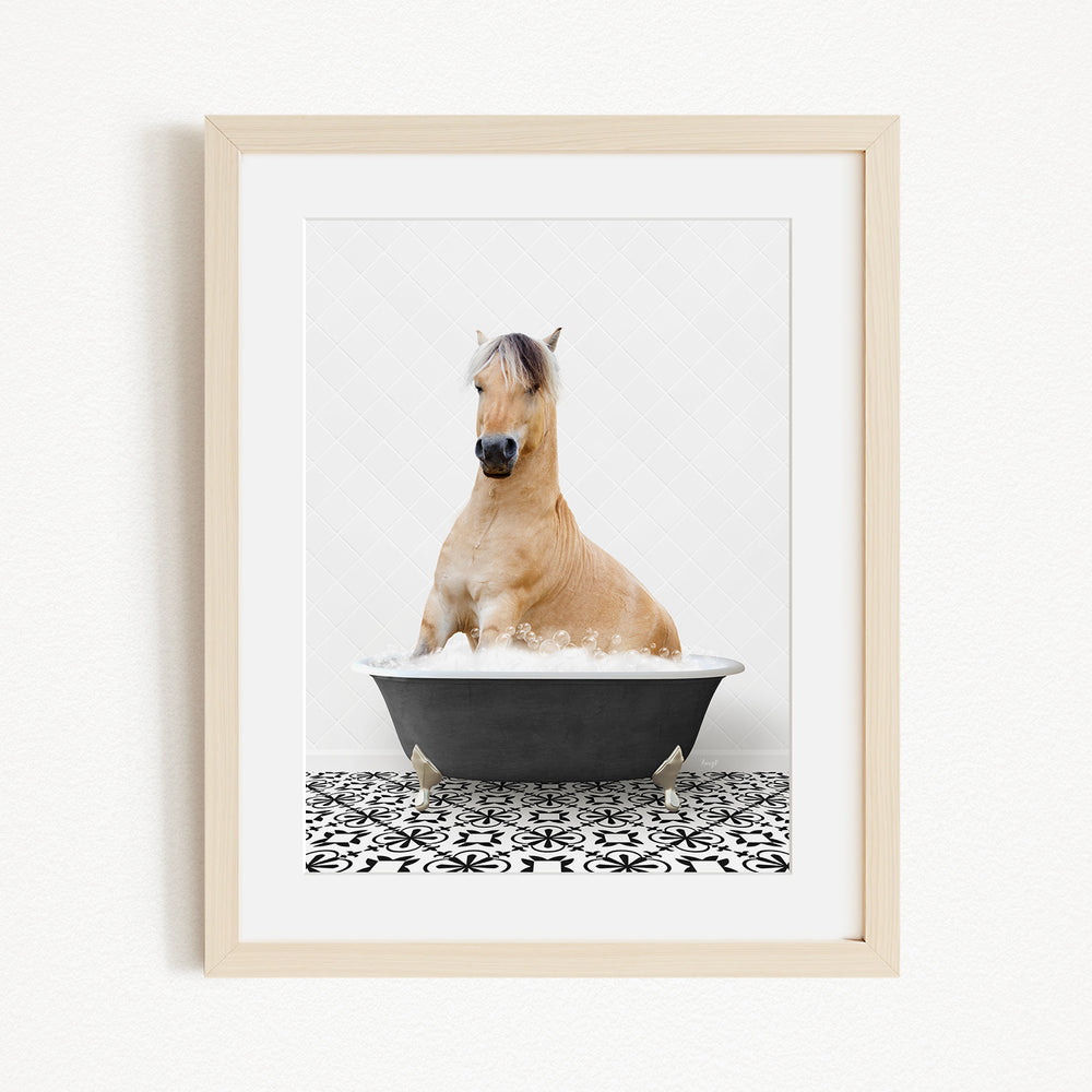 A light brown horse is sitting in a black bathtub filled with water, surrounded by a black and white patterned floor.