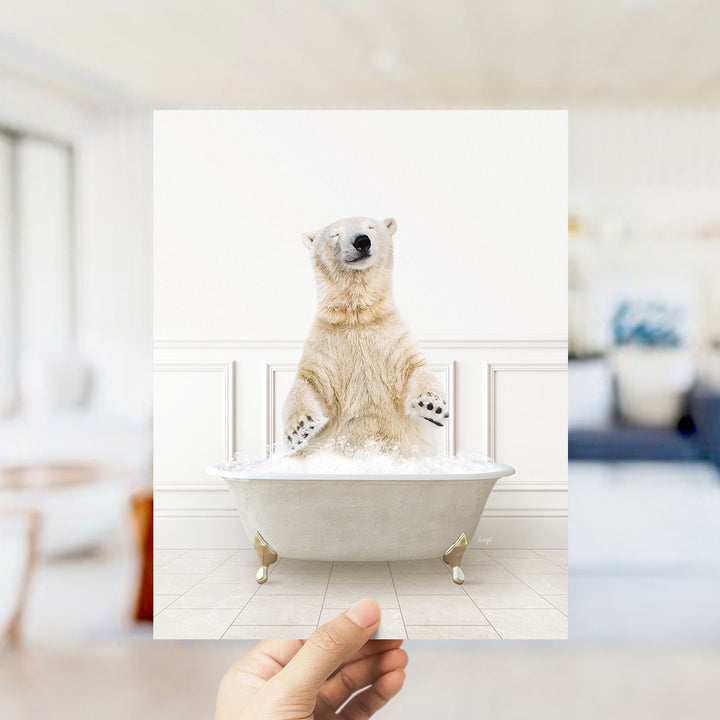 A polar bear sitting in a bathtub filled with bubbles, with a person's hand holding up the image.