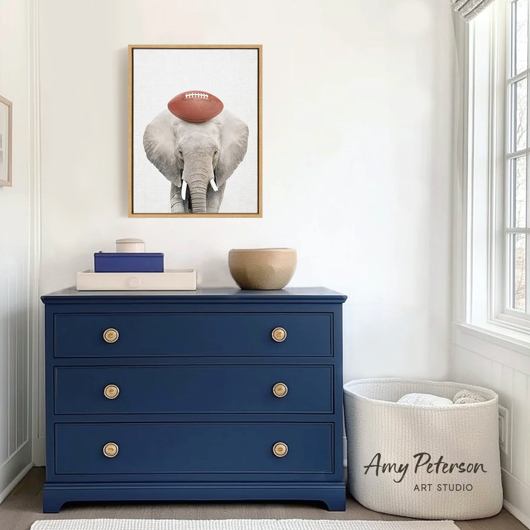 a blue dresser with a framed picture of an elephant on top, and a white basket next to it. The dresser has three drawers and a bowl on top. The wall behind the dresser has a window, and there is a sign that says " Amy Peterson ART STUDIO".