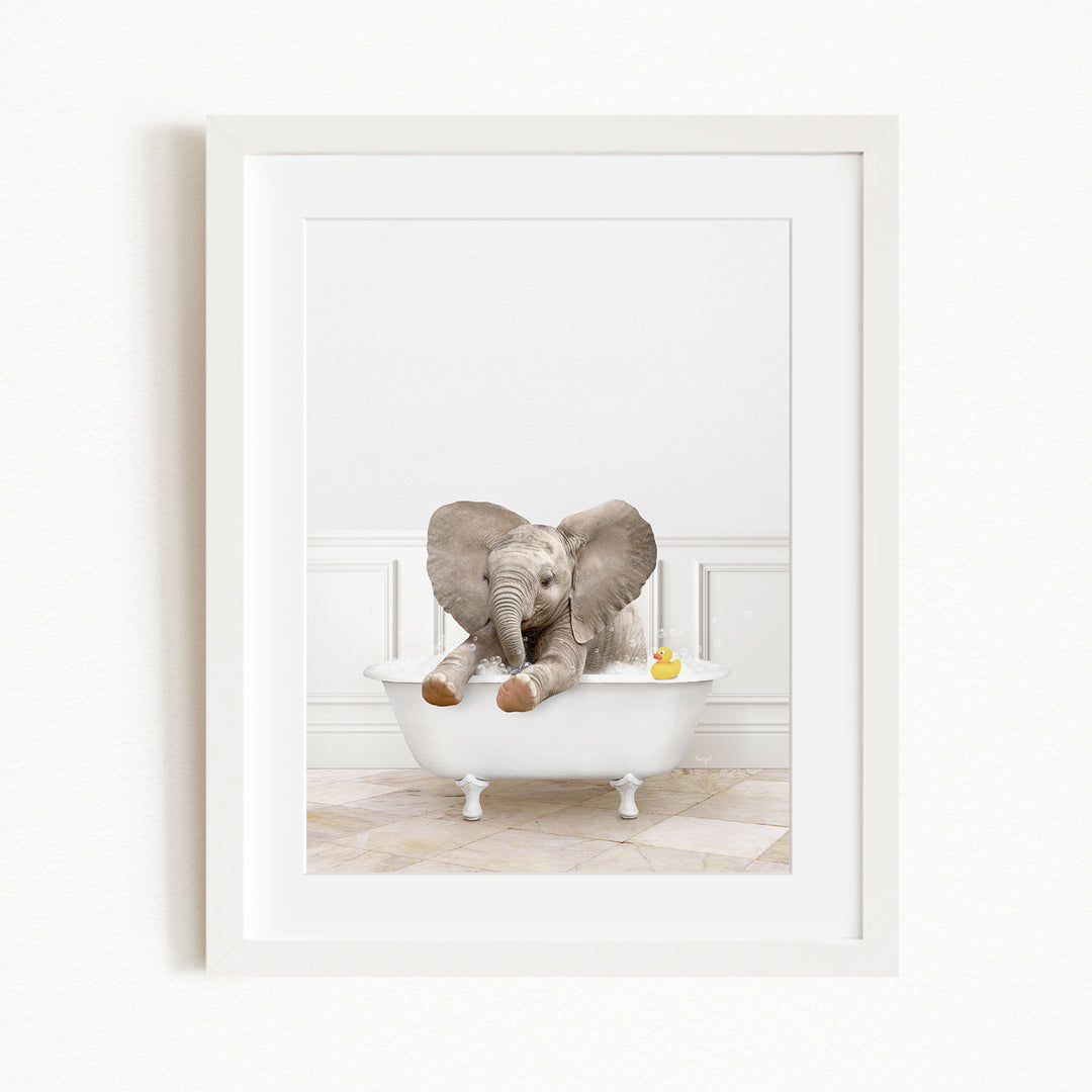 A baby elephant sitting in a white bathtub, with a yellow rubber duck floating in the water.