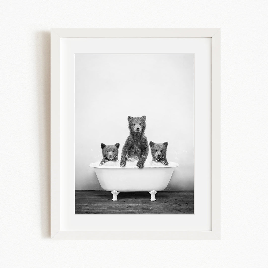 A black and white photograph of three bears sitting in a bathtub, with one bear sitting in the center and the other two bears sitting on either side.
