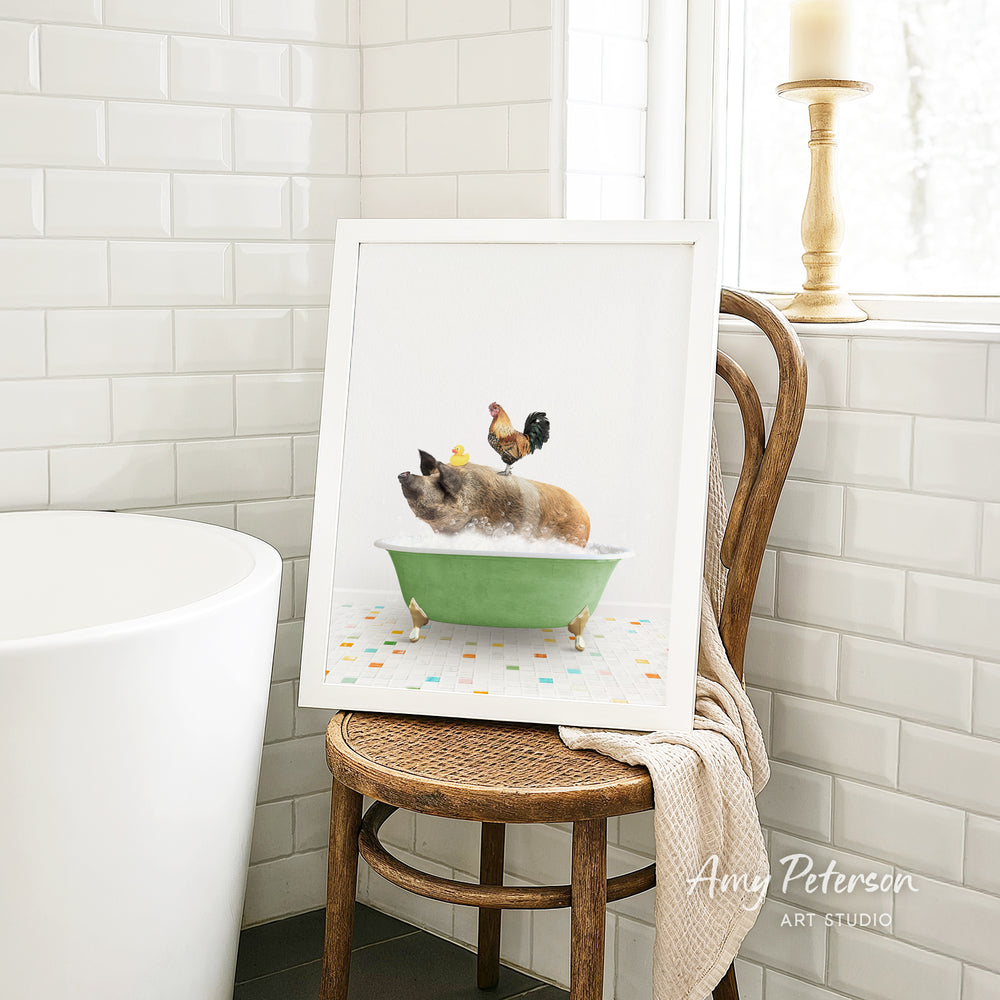 A framed image of a pig sitting in a green bathtub, with a rooster perched on its back, is displayed on a wooden chair in a bathroom setting.