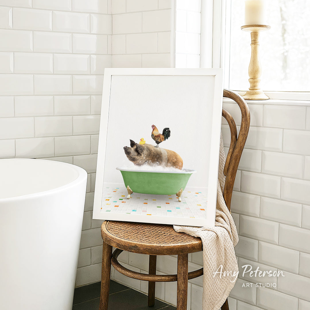 A framed image of a pig sitting in a green bathtub, with a rooster perched on its back, is displayed on a wooden chair in a bathroom setting.