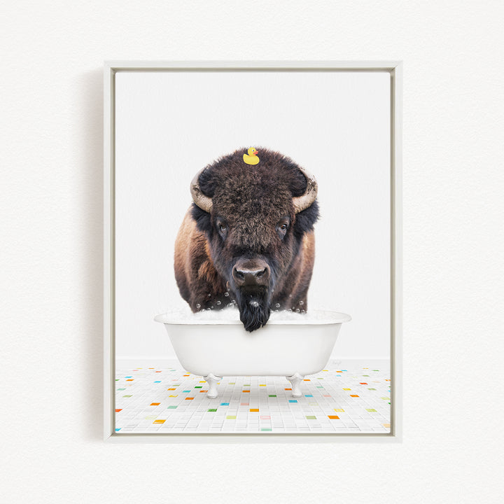 A buffalo with a yellow rubber duck perched on its head is standing in a white bathtub, creating a whimsical and playful scene.