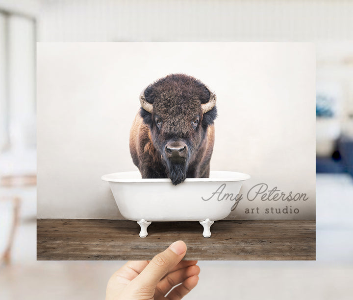 a person holding a card with a picture of a bison in a bathtub