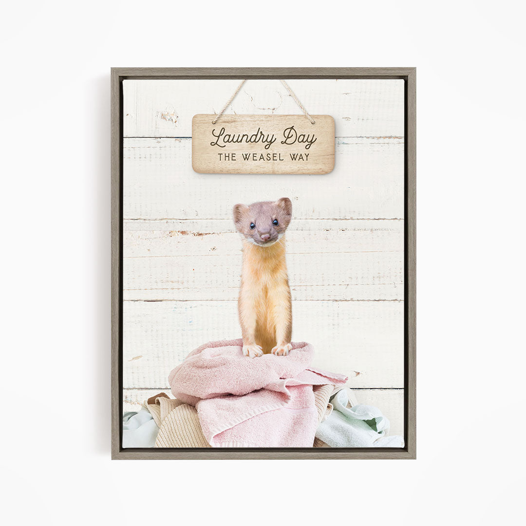 A weasel sitting on a pile of clothes, with a wooden sign above that says "Laundry Day The Weasel Way".