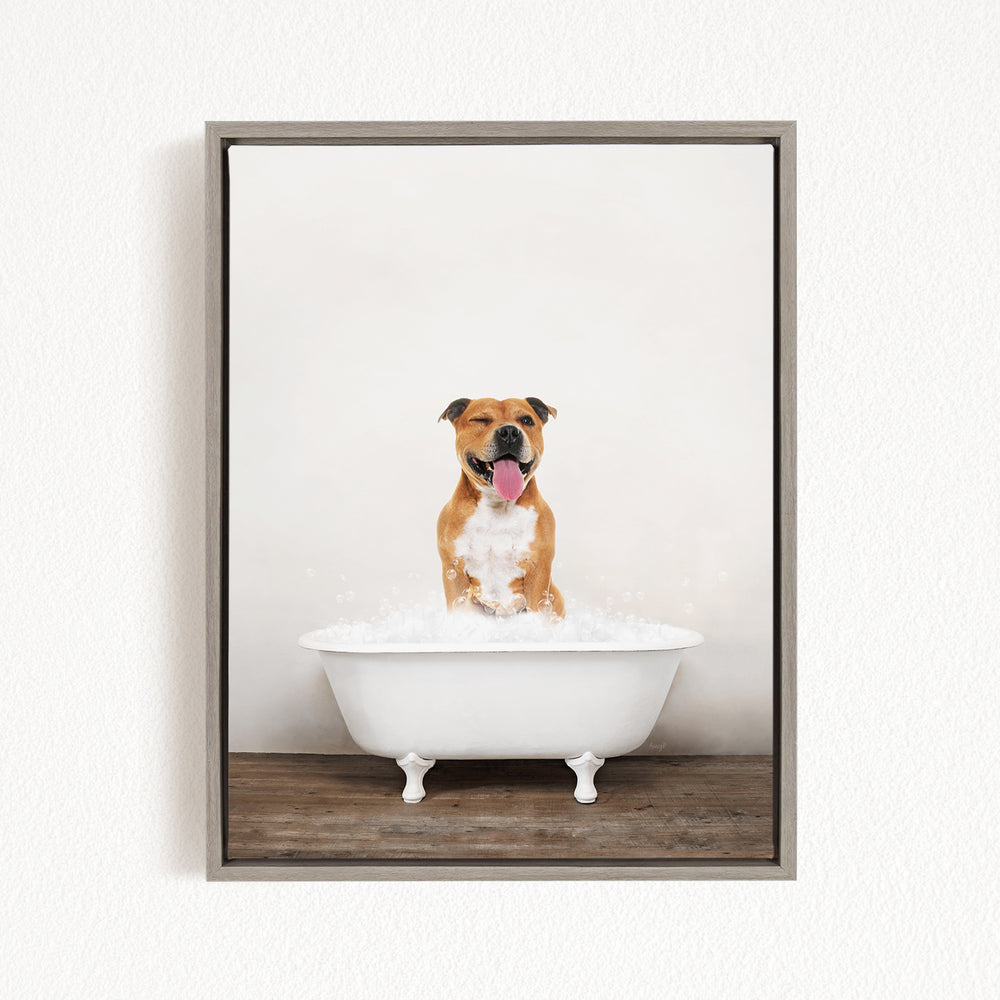 A brown and white dog sitting in a white bathtub filled with bubbles, with its tongue hanging out, creating a playful and humorous scene.