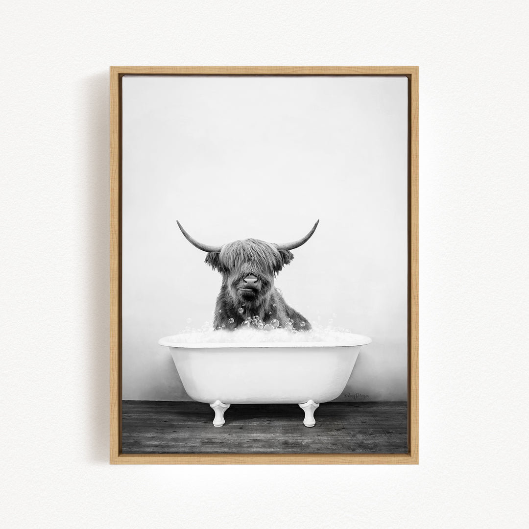 A black and white photograph of a Highland cow sitting in a bathtub filled with water.