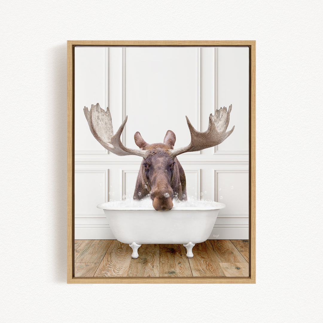 A moose with large antlers is sitting in a white bathtub, surrounded by bubbles.
