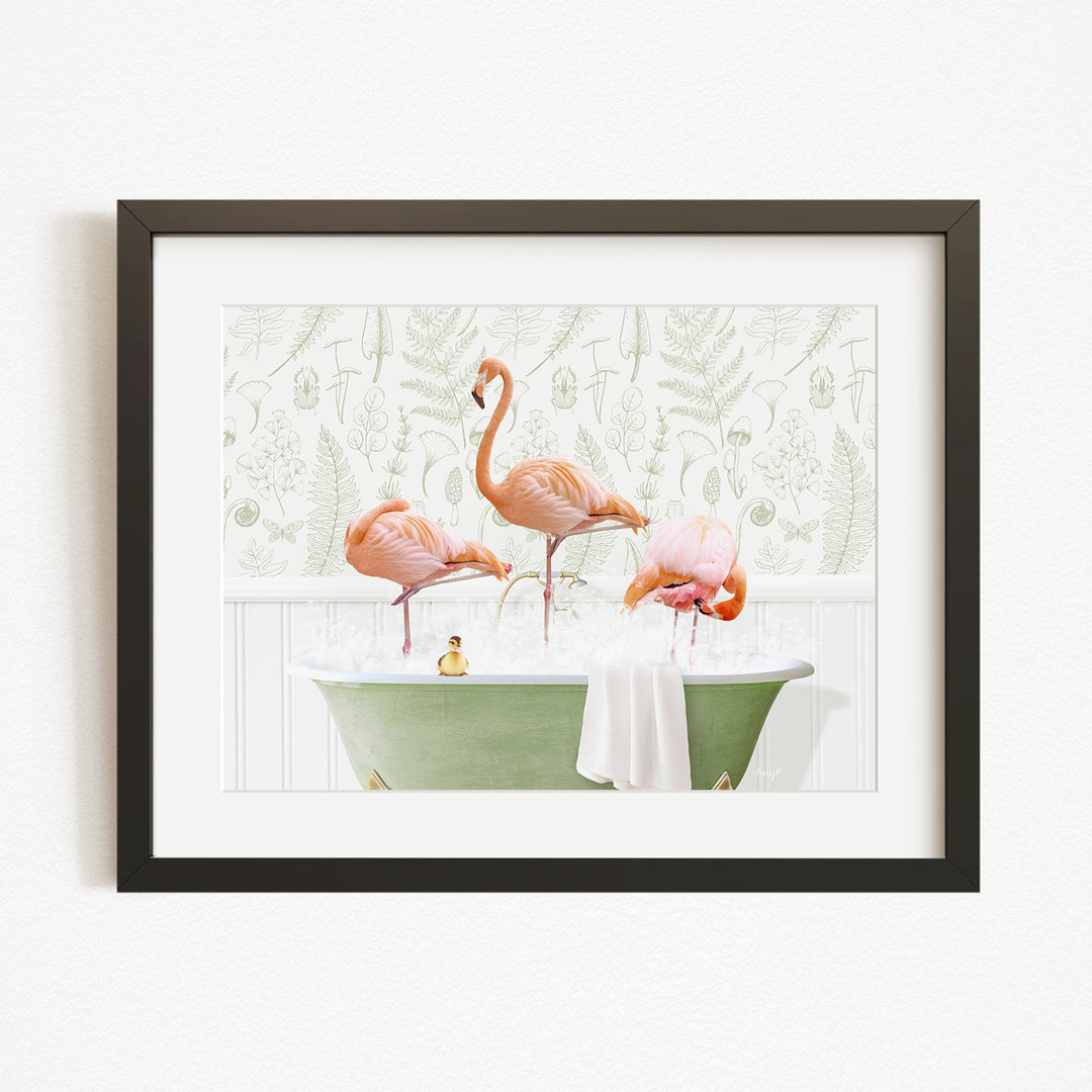 A framed image depicting three pink flamingos standing in a green bathtub filled with water, with a towel and a small rubber duck floating on the surface.