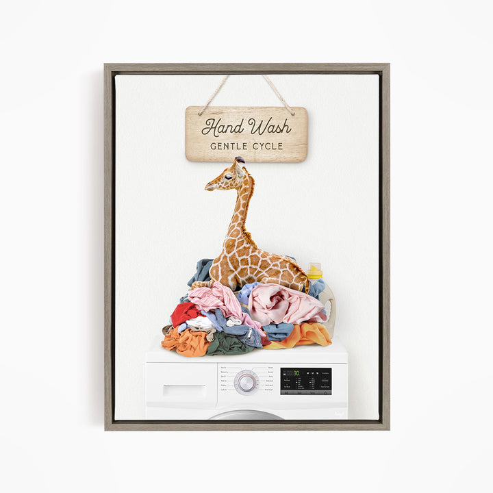 A giraffe sitting on a pile of laundry inside a washing machine, with a sign above that says "Hand Wash Gentle Cycle".