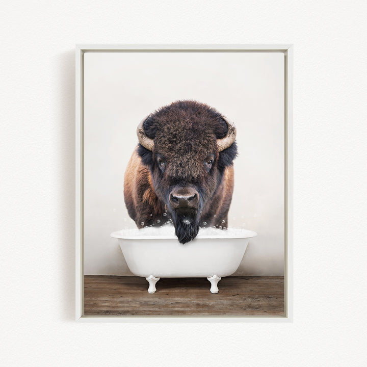 A bison with large horns is standing in a white bathtub filled with water, appearing to be enjoying a bath.