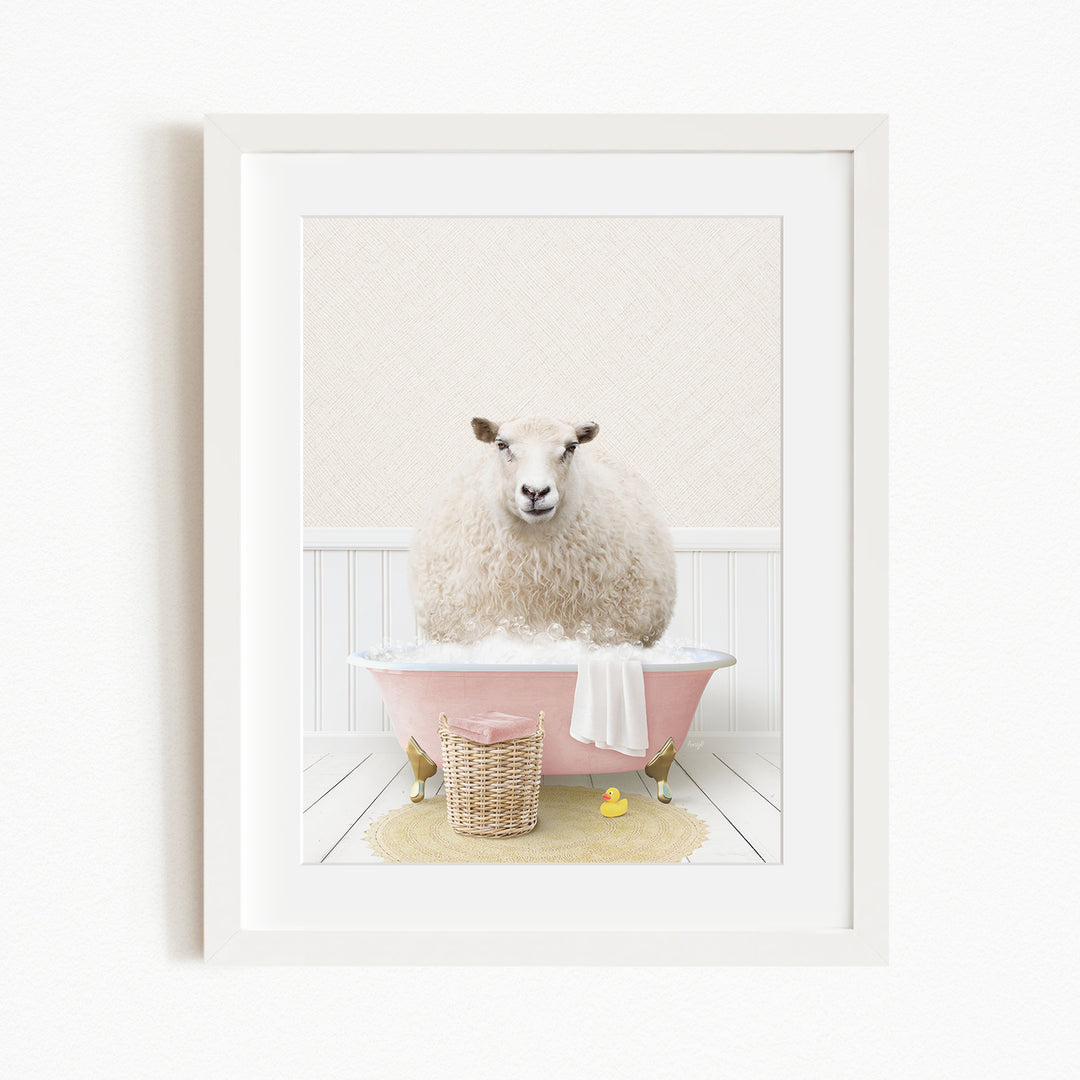 A fluffy white sheep sits in a pink bathtub, surrounded by a yellow rubber duck and a basket of towels.