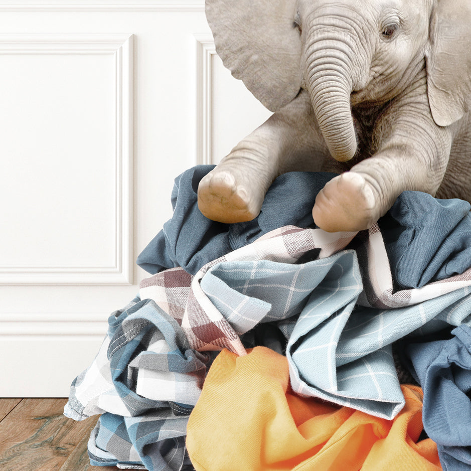 a stuffed elephant sitting on top of a pile of clothes