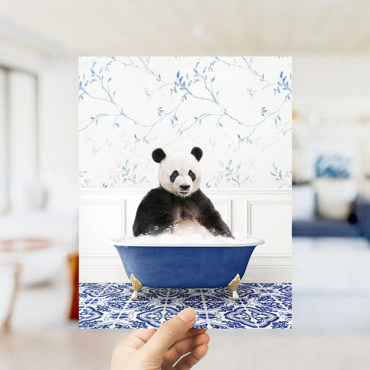 A panda bear sitting in a blue bathtub filled with bubbles, surrounded by a blue and white floral patterned wall.