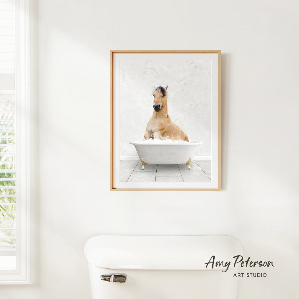 A framed image of a horse sitting in a bathtub, with a white wall and a window in the background.