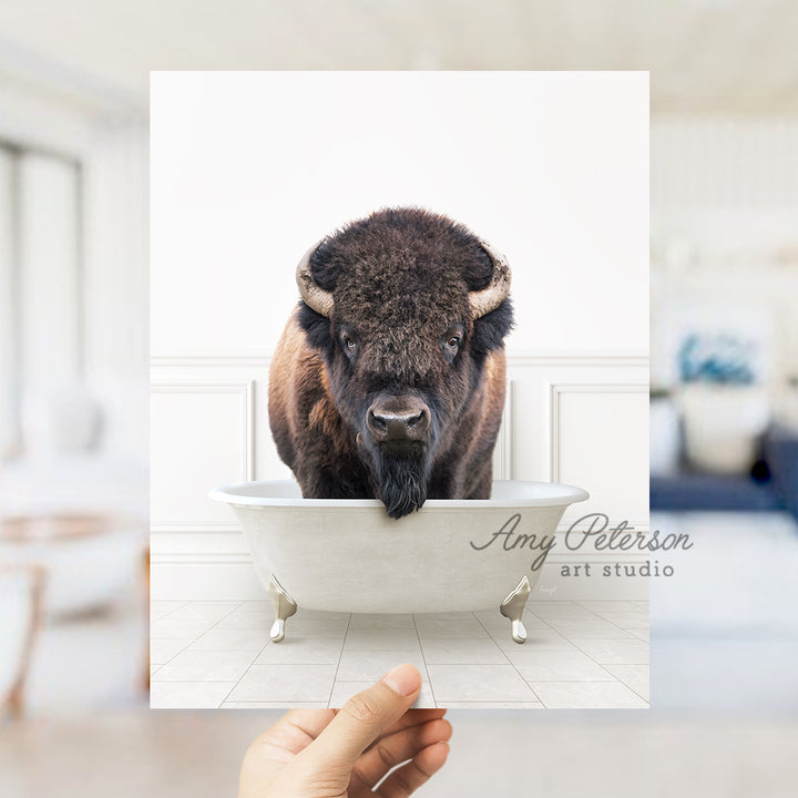 a hand holding a card with a picture of a bison in a bathtub