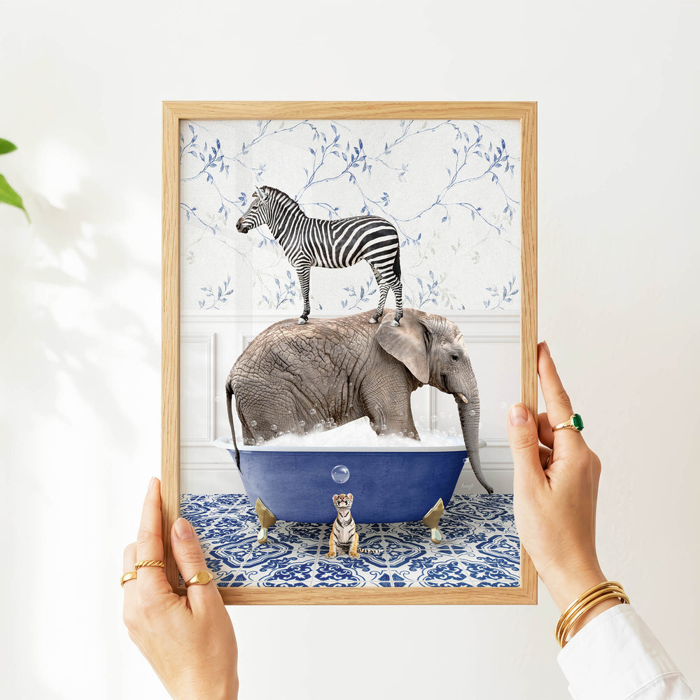 A person's hands are holding a framed picture of a zebra standing on an elephant's back, with the elephant submerged in a blue bathtub.
