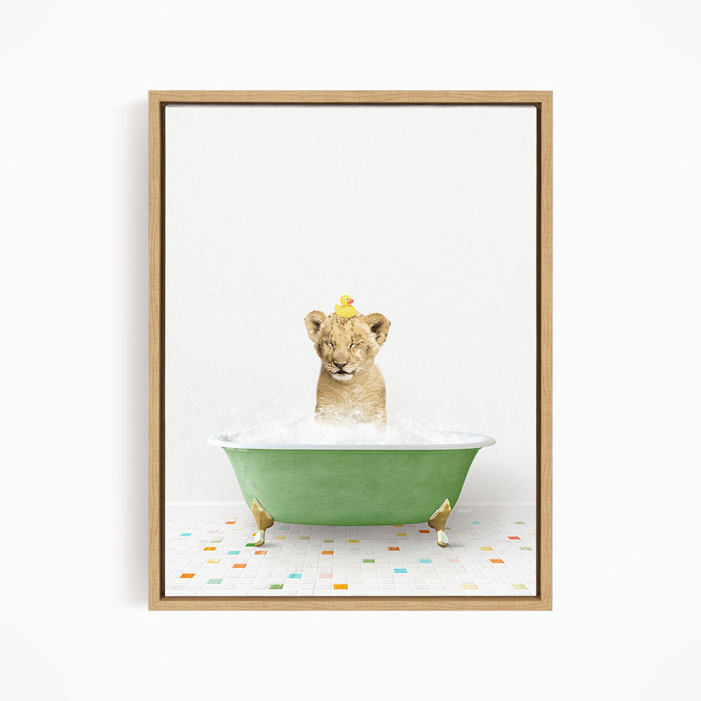 A young lion cub is sitting in a green bathtub filled with bubbles, with a yellow rubber duck perched on its head.